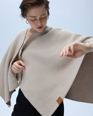 Woman arranging a taupe wool wrap over her shoulders