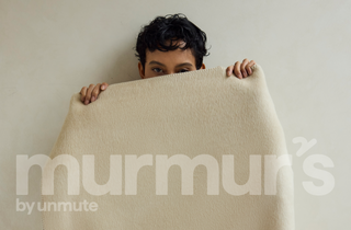 Person holding a beige blanket with 'murmur's by unmute' branding.